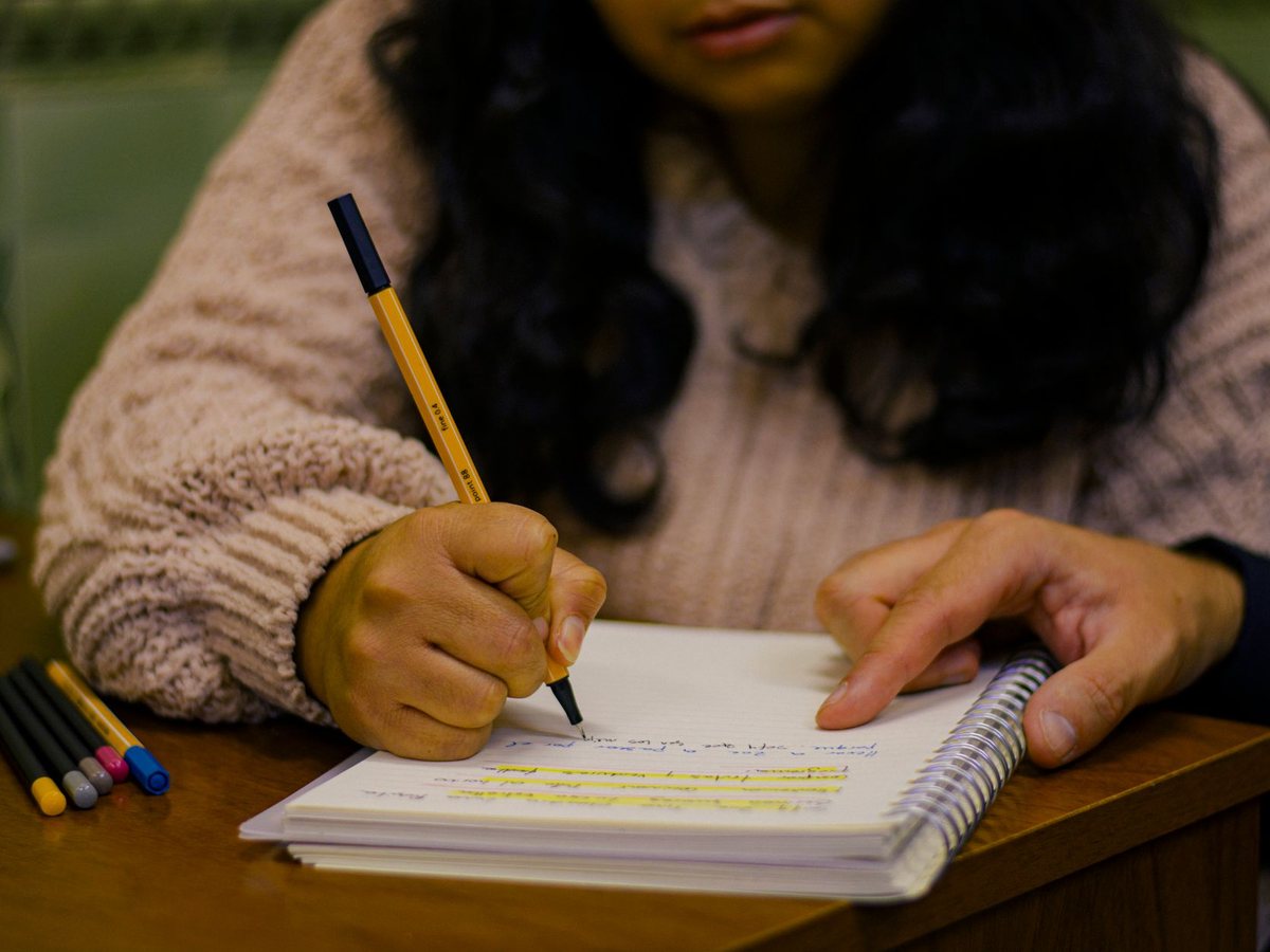 Un estudiante escribiendo en su cuaderno durante una clase