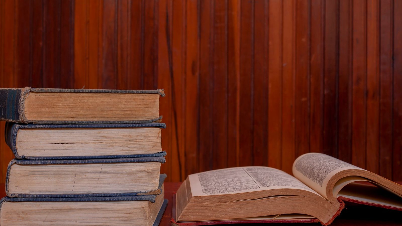 Libros antiguos y un libro abierto sobre una mesa de madera